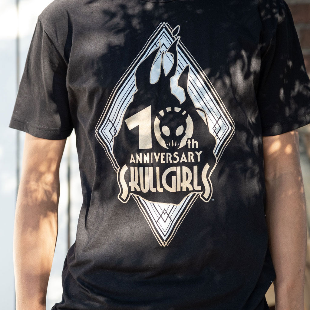 The photo shows a closeup of the Skullgirls 10th Anniversary shirt. It has sunlight peaking through some trees highlighting the design. 