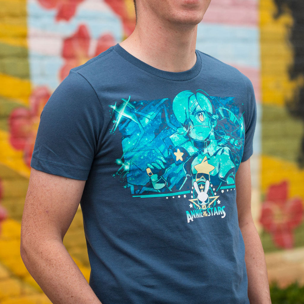 A closeup photo of the Skullgirls Annie Of The Stars tee. There is a nice blurred background of graffiti on a wall with multiple colors. 